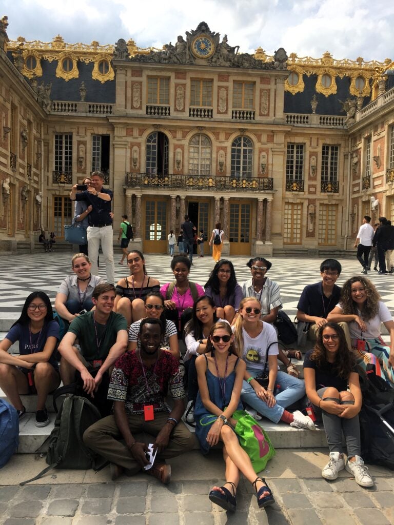 group of GU students sitting on steps in front of Chateau de Versailles