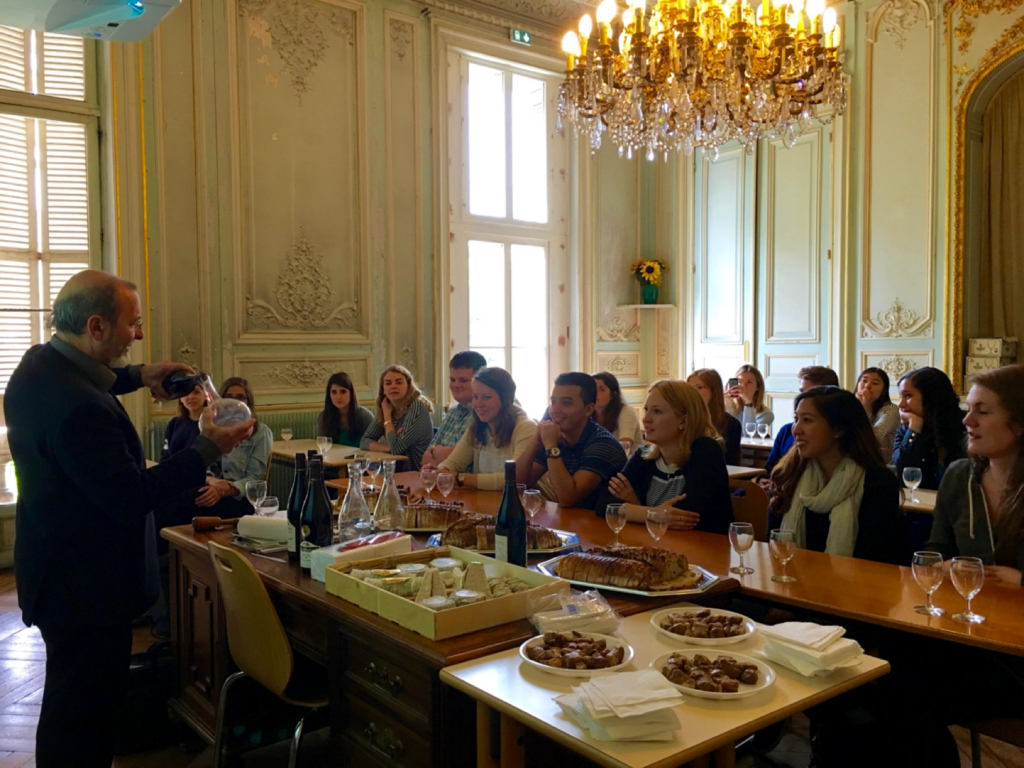 students at tables in a grand gallery in a chateau for wine tasting