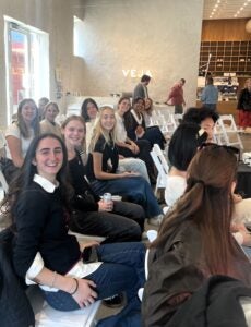 students in rows of chairs in large room with text Veja displayed on far wall