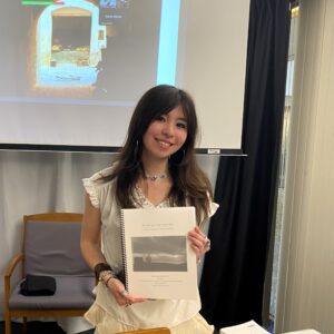 young woman smiling and holding thesis
