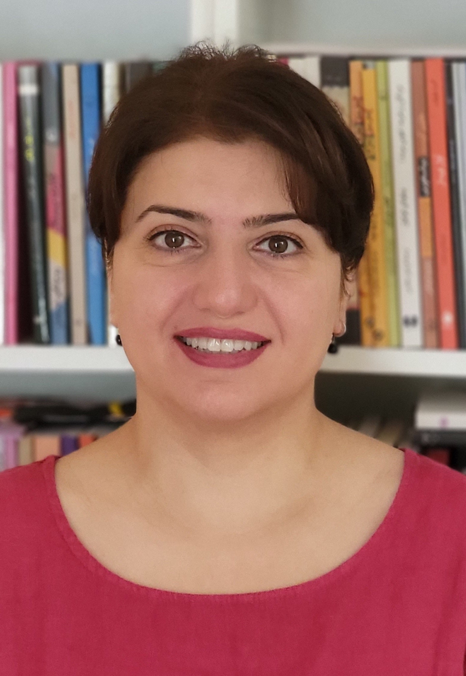 light skinned woman with dark hair standing in front of bookshelf